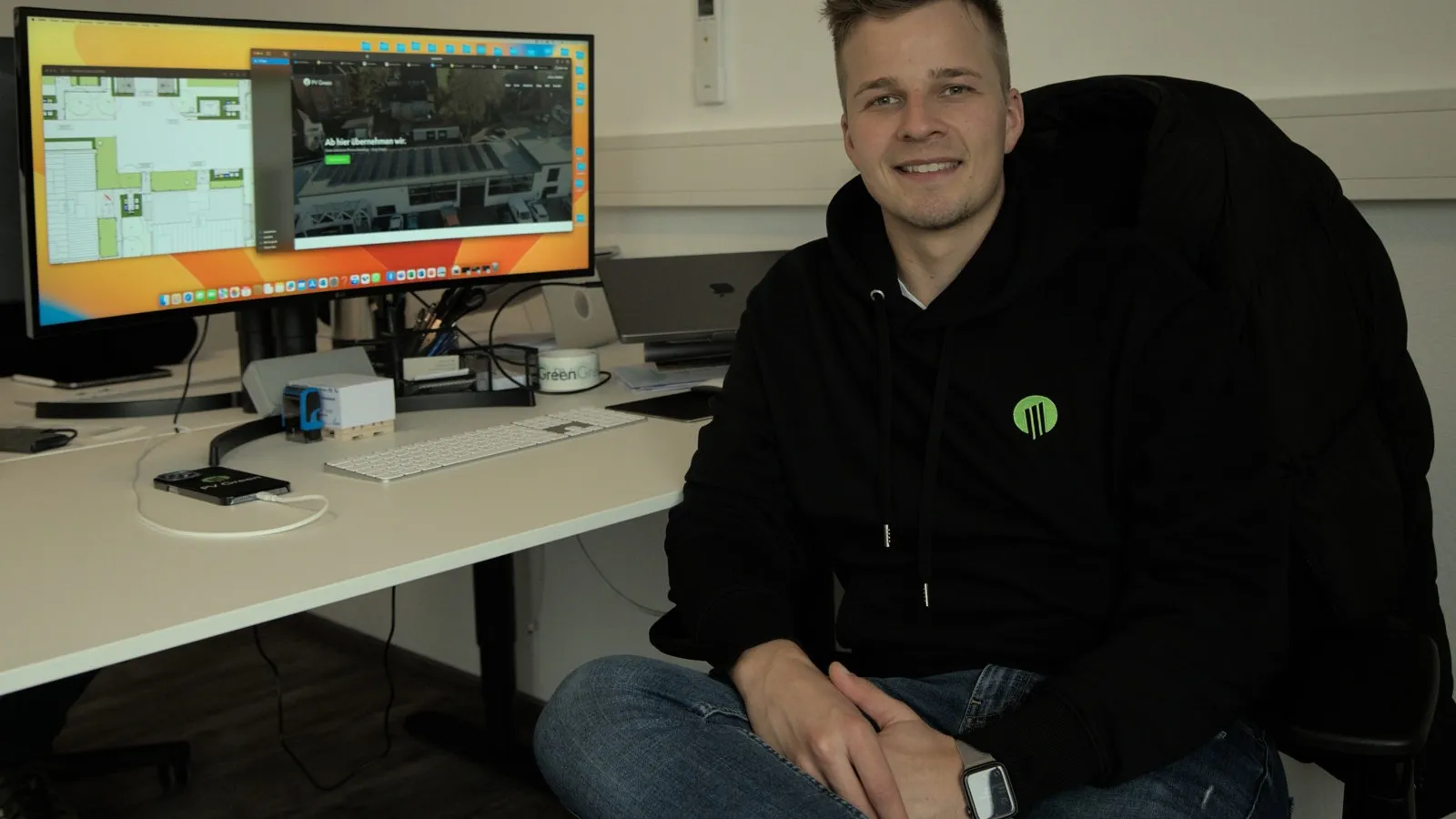 Foto von Fabio Katzor am Schreibtisch vor einem PC-Bildschirm sitzend. Er schaut in die Kamera.